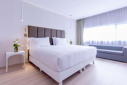 a white bedroom with a large bed and a window at NH Puebla FINSA in Puebla