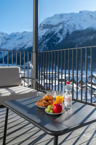 a table with a plate of food and a bottle of orange juice at Swiss Hotel Apartments - Engelberg in Engelberg
