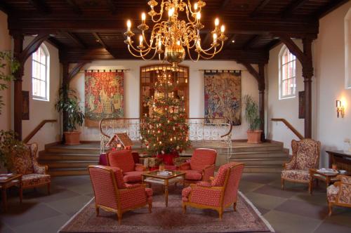 a lobby with a christmas tree and chairs and a chandelier at Hotel Altes Gymnasium in Husum
