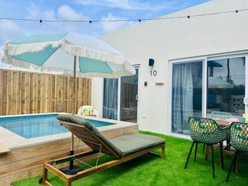 a patio with a chair and an umbrella and a pool at Vistalmar Ocean Suites in Oranjestad
