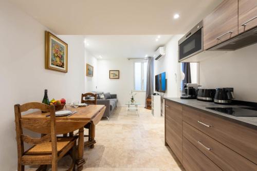 Il dispose d'une cuisine et d'un salon avec une table en bois et une salle à manger. dans l'établissement 1-Br Apartment with AC in the Heart of Cannes, à Cannes