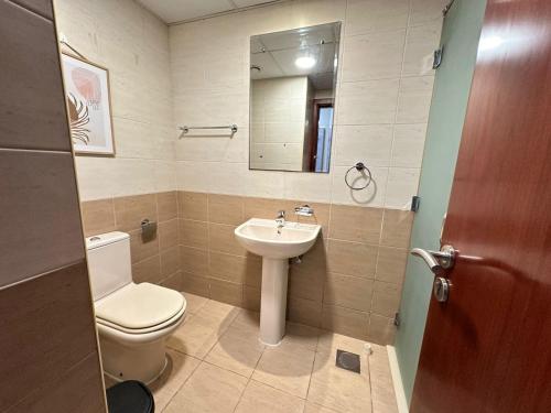 a bathroom with a toilet and a sink and a mirror at Lagoon Studio Apartment - Nexus Holiday Homes in Ras al Khaimah