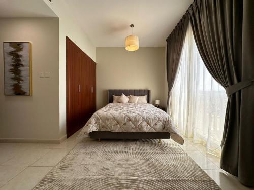 a bedroom with a bed and a large window at Lagoon Studio Apartment - Nexus Holiday Homes in Ras al Khaimah