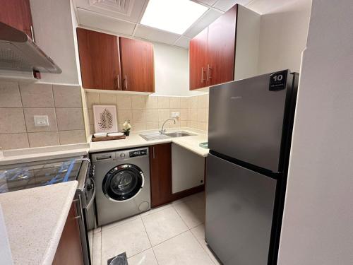a kitchen with a refrigerator and a washing machine at Lagoon Studio Apartment - Nexus Holiday Homes in Ras al Khaimah