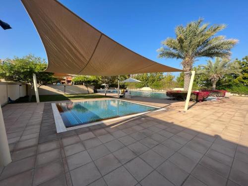 a swimming pool with a large umbrella over it at Lagoon Studio Apartment - Nexus Holiday Homes in Ras al Khaimah