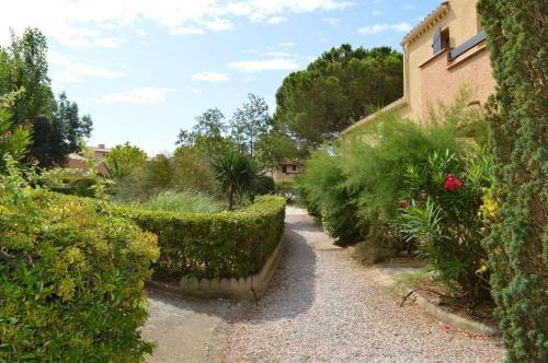 un jardin avec des buissons et des arbres et un bâtiment dans l'établissement Appartement Studio cabine 4 couchages SAINT CYPRIEN SC070-065, à Saint Cyprien Plage
