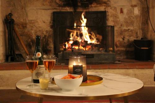 - une table avec deux verres de vin et une cheminée dans l'établissement Le Mont Roty - 15min Deauville - 15P, à Saint-Étienne-la-Thillaye