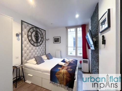 - une chambre dotée d'un lit avec une horloge murale dans l'établissement Urban Flat 21 - Chaplin Atelier in central Paris, à Paris