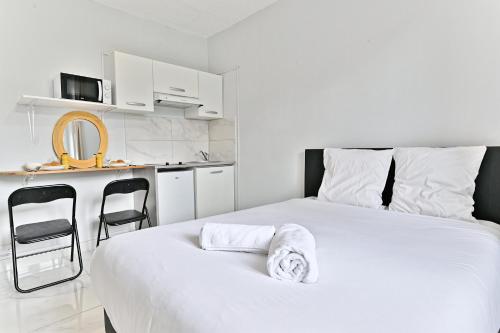 Cet appartement comprend une chambre avec un lit blanc et une cuisine. dans l'établissement Montmartre - Studio Sacré Cœur - III, à Paris