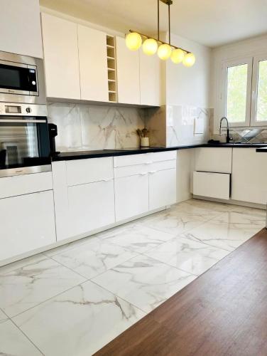 - une cuisine avec des placards blancs et un sol en marbre dans l'établissement Gare du Nord - Large renovated apartment, à Paris