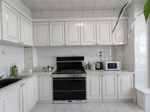 a kitchen with white cabinets and a black stove top oven at 比邻中央大街江景公寓 楼下松花江 索道 地铁 防洪纪念塔 in Harbin