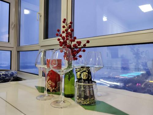 a table with two wine glasses and a vase with flowers at 比邻中央大街江景公寓 楼下松花江 索道 地铁 防洪纪念塔 in Harbin