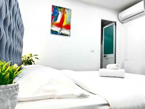 a white bedroom with a bed and a painting on the wall at Tirana Square Hotel in Tirana