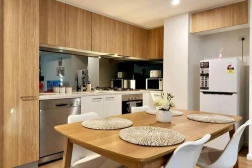 a kitchen with a wooden table and white appliances at Modern 2BR Apt Adelaide CBD with Pool-Gym-BBQ in Adelaide