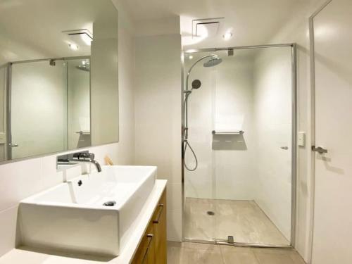 a white bathroom with a sink and a shower at Modern 2BR Apt Adelaide CBD with Pool-Gym-BBQ in Adelaide