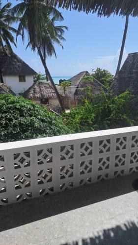 a white fence with trees and houses in the background at Lala House by Masala Living in Jambiani