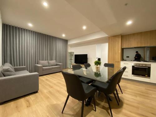 a living room with a table and chairs and a couch at Luxury 3 BR Apt with Pool-Gym-Sauna-Steam Room in Adelaide