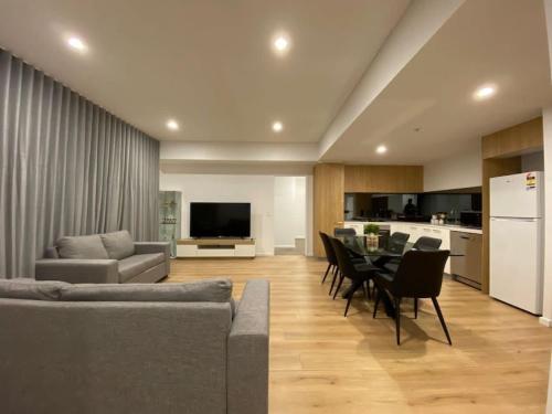 a living room with a couch and a table with chairs at Luxury 3 BR Apt with Pool-Gym-Sauna-Steam Room in Adelaide