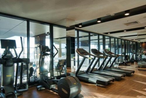 a gym with a row of treadmills and mirrors at Luxury 3 BR Apt with Pool-Gym-Sauna-Steam Room in Adelaide