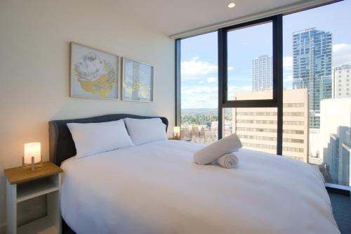 a bedroom with a large white bed with a large window at Paradise 2BR Apt in Rundle Mall in Adelaide