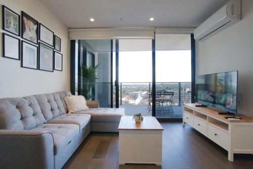 a living room with a couch and a tv at Paradise 2BR Apt in Rundle Mall in Adelaide