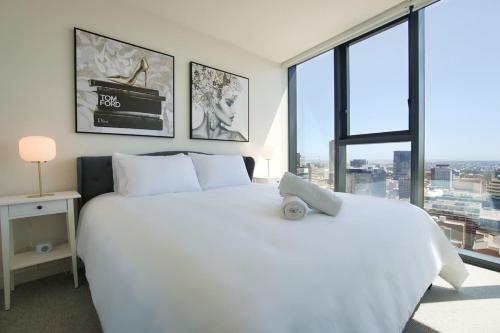 a bedroom with a large white bed and large windows at Serenity in the Sky - 2BR Apt in Rundle Mall in Adelaide