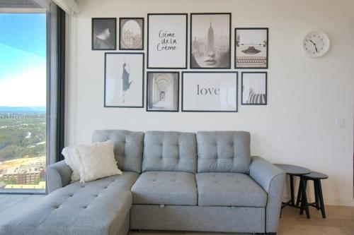 a living room with a couch and pictures on the wall at Serenity in the Sky - 2BR Apt in Rundle Mall in Adelaide