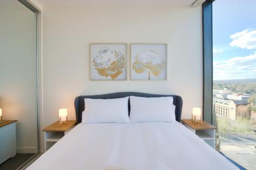 a bedroom with a white bed and a large window at Paradise 2BR Apt in Rundle Mall in Adelaide
