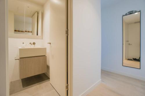 Rundle Retreat - 2BR Apartment with stunning views في أديلايد: حمام مع حوض ومرآة