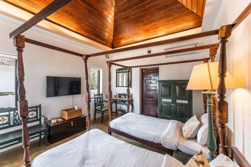 a bedroom with two beds and a flat screen tv at Villa Naina, Marari beach in Alleppey