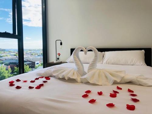 two swans in a bed with roses on it at Modern 2 Bedroom Apartment - Adelaide CBD in Adelaide