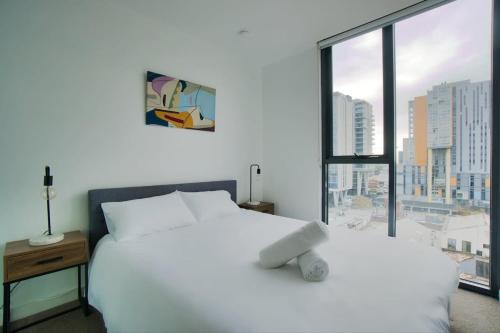 a white bed in a room with a large window at Modern 2 Bedroom Apartment - Adelaide CBD in Adelaide