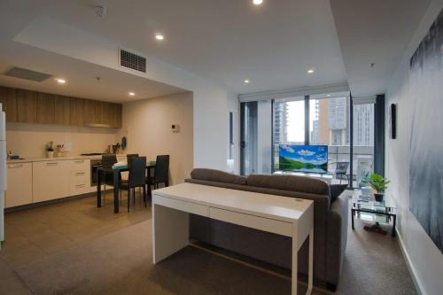 a living room with a couch and a table in a kitchen at Modern 2 Bedroom Apartment - Adelaide CBD in Adelaide