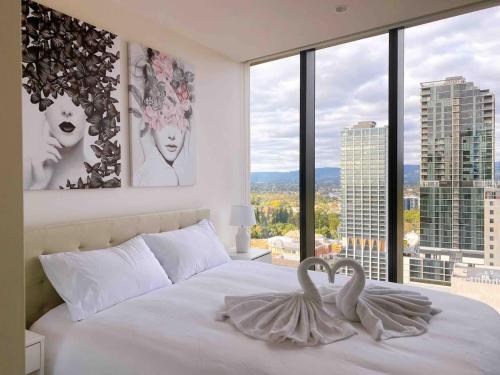a bedroom with a white bed with two swans on it at Queen Bed Luxury Parisian Paradise with Amazing City Views & Gym in Adelaide
