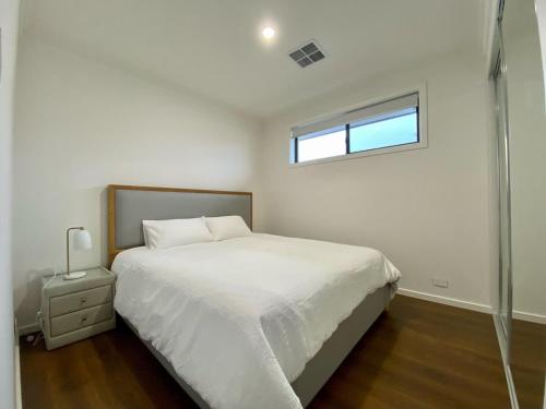 a white bedroom with a bed and a window at New Spacious Luxury 5 Bedroom Mansion in Unley in Unley