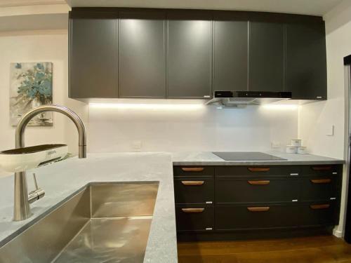 a kitchen with black cabinets and a sink at New Spacious Luxury 5 Bedroom Mansion in Unley in Unley