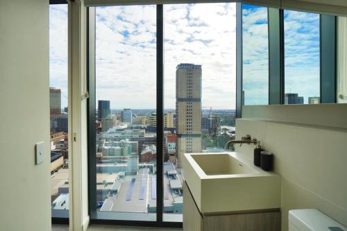 a bathroom with a view of a city from a window at Nintendo Theme-Adelaide CBD-King Bed-Gym-BBQ in Adelaide