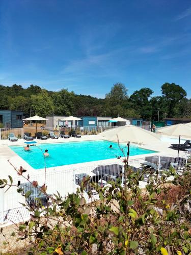 une grande piscine avec chaises et parasols dans l'établissement Terres de France - Domaine de Kerioche, à Rochefort-en-Terre