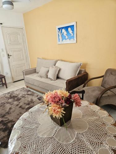 a living room with a couch and a table with flowers on it at Chalé das Conchas in Cabo Frio