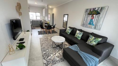 a living room with a black couch and a table at Sonrise Stays in Gaborone