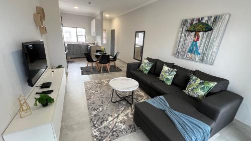a living room with a black couch and a table at Sonrise Stays in Gaborone