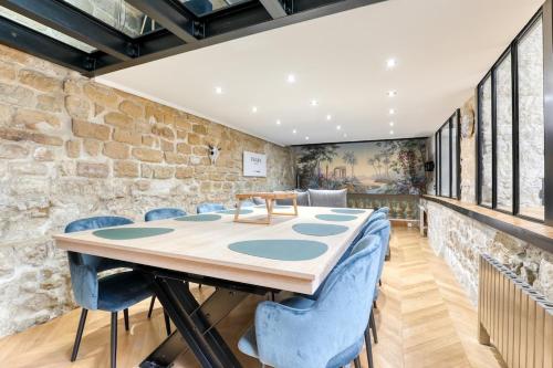 une table et des chaises dans une pièce avec un mur en pierre dans l'établissement Beautiful loft 130m2 Louvre Palais Royal - II, à Paris