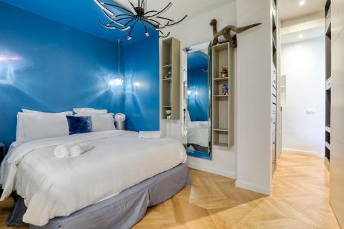 une chambre avec un grand lit avec un mur bleu dans l'établissement Beautiful loft 130m2 Louvre Palais Royal - II, à Paris