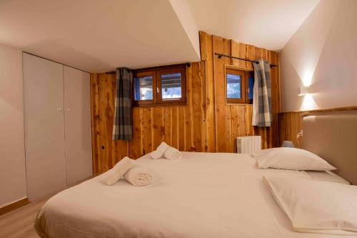 - une chambre avec un lit blanc, des murs en bois et des fenêtres dans l'établissement Chalet Lougarou - Plagne 1800 - 8 personnes - ski au pied, à La Plagne Tarentaise
