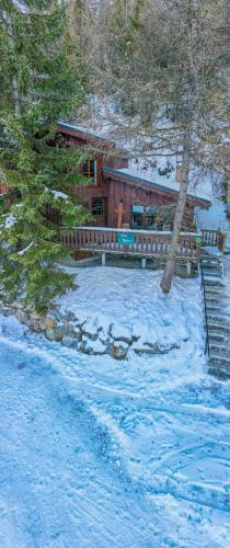 une cabane en rondins dans la neige avec une terrasse couverte dans l'établissement Chalet Lougarou - Plagne 1800 - 8 personnes - ski au pied, à La Plagne Tarentaise