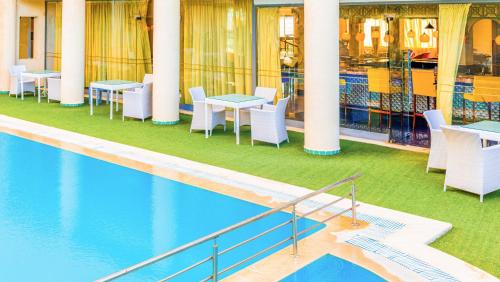 Una piscina con mesas y sillas al lado de un edificio. en César Palace Sousse, en Sousse