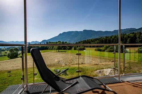 a chair on a balcony with a view of a field at Naturresort FiSCHERGUT - Lodge Wolfgangthal in St. Wolfgang