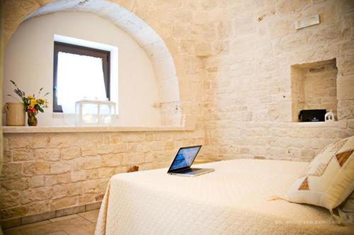 a bedroom with a bed with a laptop on it at Trulli Magravì - Apparthotel in Alberobello