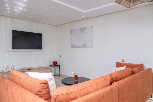 a living room with two orange couches and a tv at Very Charming Apartments with balcony, Haut Agdal in Rabat