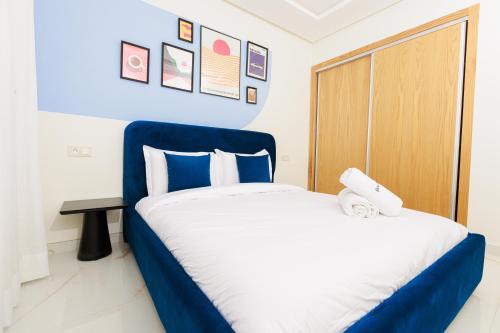 a bedroom with a bed with blue and white sheets at The lodge Residence by Goodmove - Hay Riad in Rabat